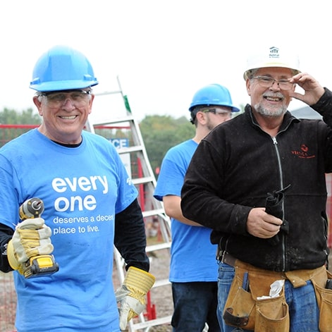 Brad and other employees smiling at camera while working on house construction for Habitat for Humanity.